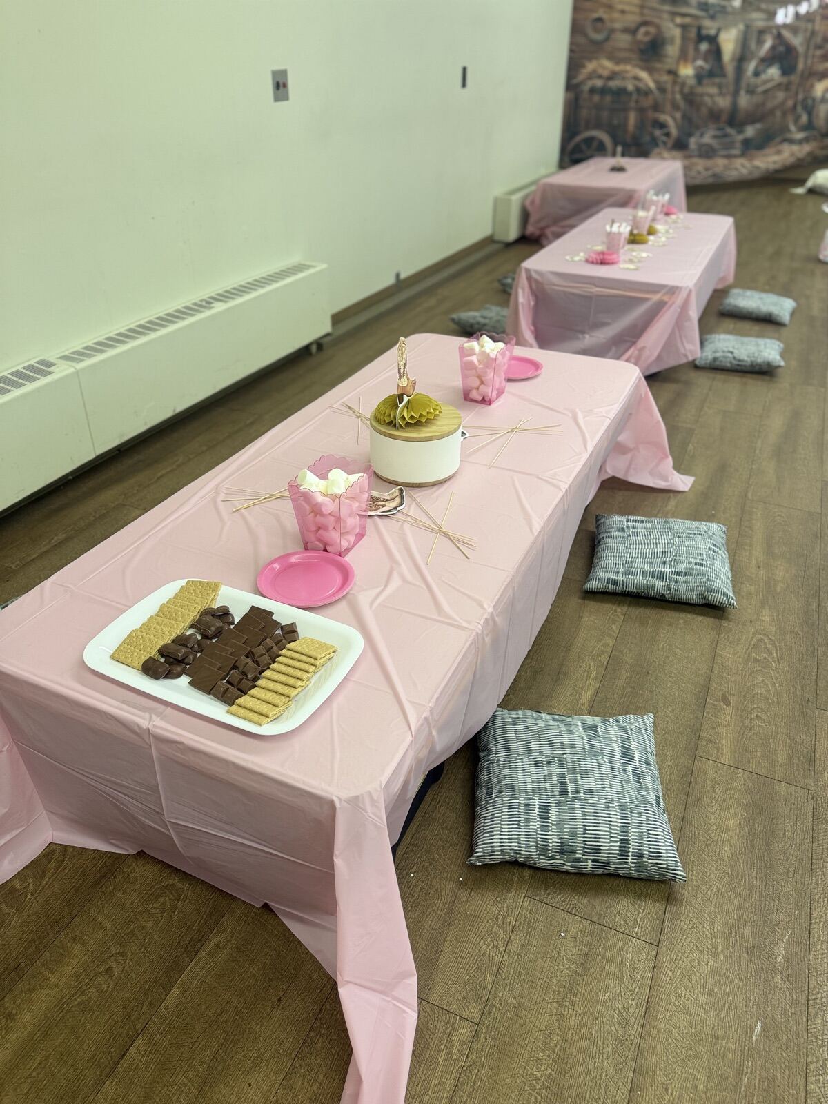 Low tables with pink tablecloths and floor cushions set for a kids' birthday party