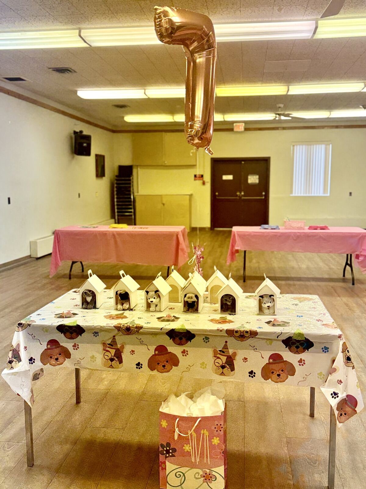 A party table with a gold number 7 balloon and small treat houses in the main hall