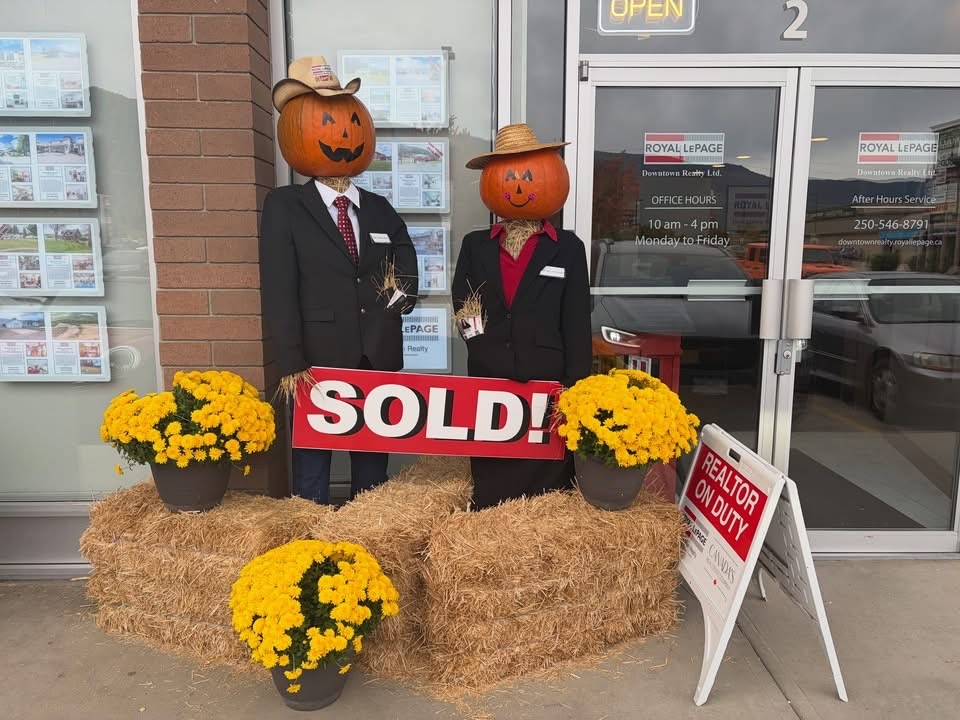 Pumpkin-headed scarecrows in suits outside Royal LePage Downtown Realty in Armstrong